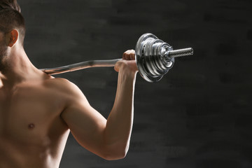 Sporty man doing exercises with barbell on dark background, closeup