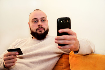 Man paying with credit card on smartphone at home