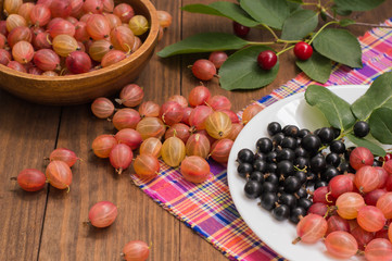Gooseberries and currants on a wooden background. Top view. Close-up