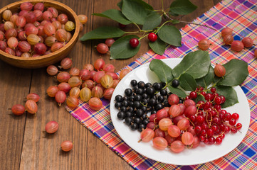 Gooseberries and currants on a wooden background. Top view. Close-up