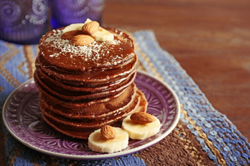 Tasty pancakes with banana, almond and chocolate sauce on plate