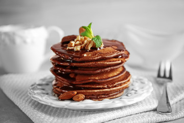 Tasty pancakes with nuts and chocolate sauce on plate