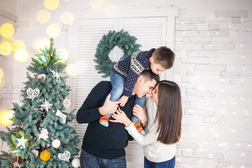 Family of mother, father and little child near Christmas tree with presents, decorations and New Year or Christmas