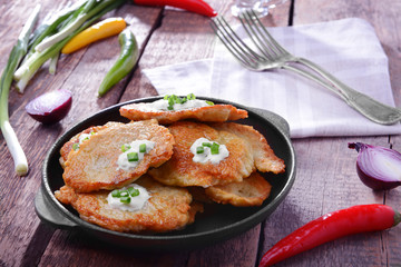 Pan with tasty potato pancakes for Hanukkah and some ingredients on wooden table