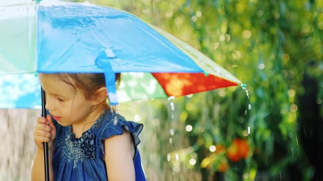 Cheerful little girl of three years standing under an umbrella
