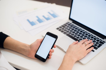 Close Up of woman hands using mobile phone and laptop computer with blank copy space screen for your advertising text message or content business.