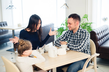 Couple fighting in front of child at cafe or restaurant.