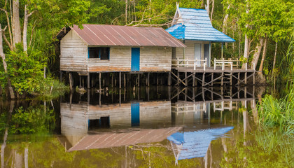 Fototapeta na wymiar Two small house on the slings are over a calm river and reflected it in Indonesia