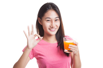 Young Asian woman drink orange juice show OK sign.