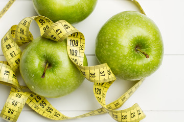 Manzanas verdes con cinta métrica sobre fondo blanco. Vista superior