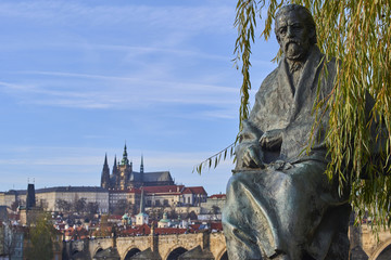 Statue of Bedrich Smetana infront of The Bedrich Smetana Museum. Charles Bridge, Prague Castle and St. Vitus Cathedral on background. - obrazy, fototapety, plakaty