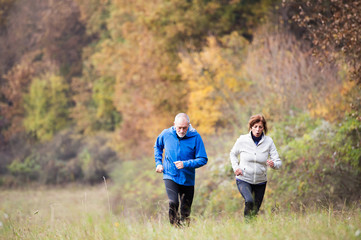Fototapeta na wymiar Beautiful senior couple running outside in sunny autumn nature