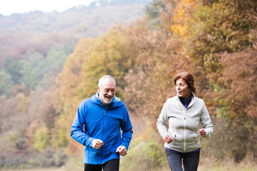 Naklejka premium Beautiful senior couple running outside in sunny autumn nature