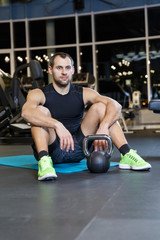 Athletic guy doing exercise with weights at the gym