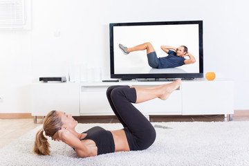 femme qui fait des abdos devant un cours à la télévision