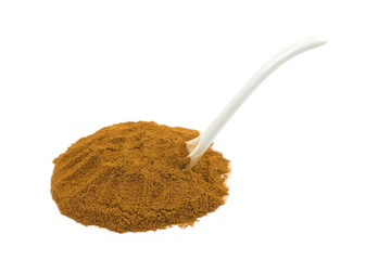 Spoon in heap of cinnamon powder on white