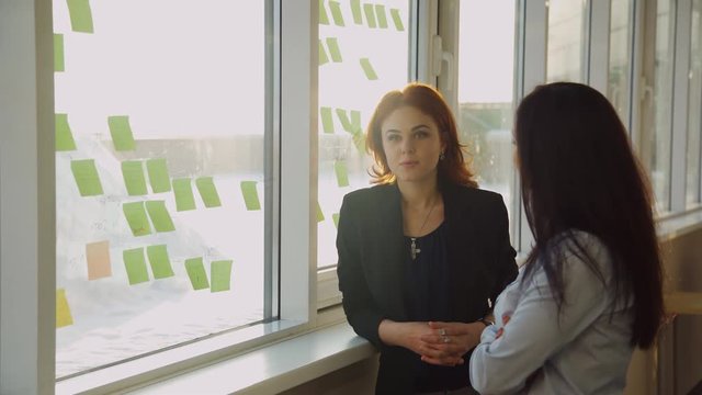 Two office workers discussing stickers pasted on window