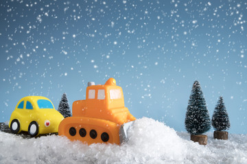 Snow plow. Toy car in a little winter landscape. Concept of road cleaning and road safety.