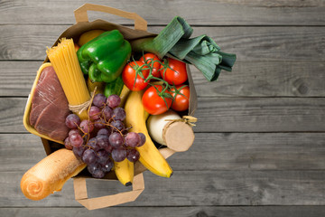 Paper bag of groceries on wooden table with copy space