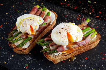 Grilled Toast witch Asparagus, Poached egg, bacon on stone background