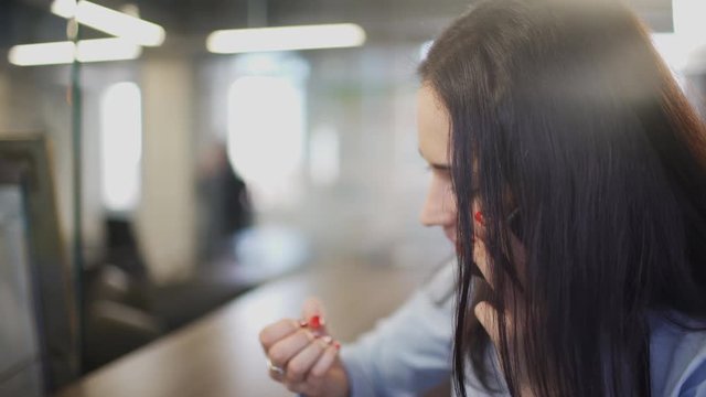 Brunette woman in office talking on telephone during break indoors.