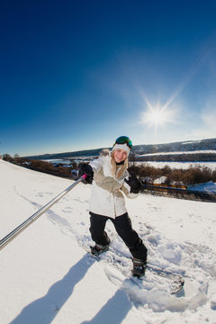 Young woman with the snowboard shooting a selfie by her action camera