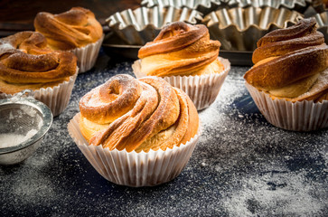 Modern fashionable pastries - scones cruffins  (puffmaffin), a mixture of a croissant and maffin. On blue dark wooden table, sprinkled with powdered sugar. Copy space