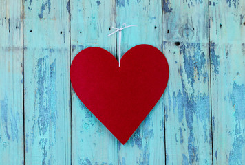 Large red heart hanging on teal blue wood background