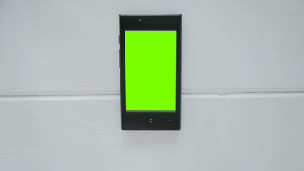 Smartphone with green screen on white wooden background