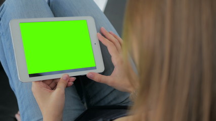 Woman looking at horizontal tablet computer with green screen. Close up shot of woman's hands with pad