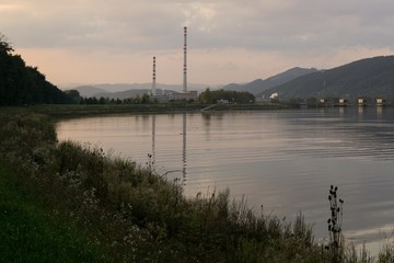 Fototapeta na wymiar Chimneys of town and clouds with reflections in water reservoir on river Vah. Slovakia