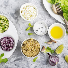 Ingredients for a light salad of quinoa, cucumber, cheese and sweet red onion with butter  lettuce on   gray background. Top view. Greenery