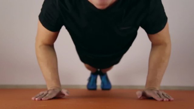 Athlete doing pushups in the gym, his face very tense
