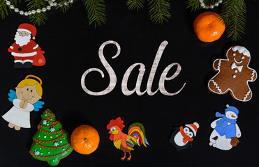 Xmas composition with text Sale on school blackboard and the Christmas decorations, toys (Santa Claus, Angel, a rooster, a snowman, a penguin) and tangerine