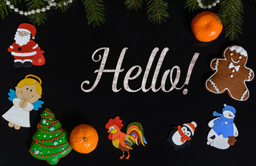 Xmas composition with text Hello on school blackboard and the Christmas decorations, toys (Santa Claus, Angel, a rooster, a snowman, a penguin) and tangerine