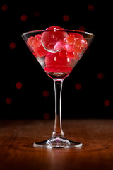 Christmas card: martini glass with balls on bokeh background in