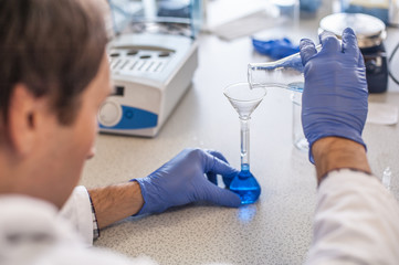 Male laboratory researcher performs tests with blue liquid
