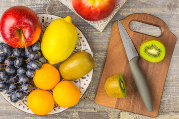 Apple Orange, lemon, fruit, KIWI, the plate and wooden Board. Knife grapes background on a  table.