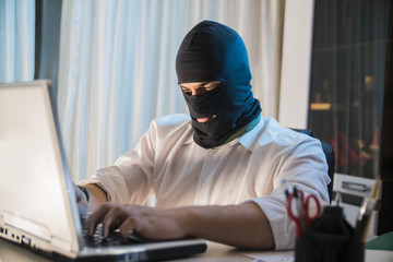 the thief hacker working on laptop in the night stealing data