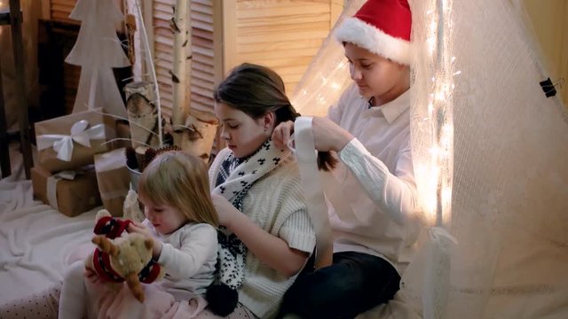 Brother Braided Pigtails to to His Little Sister in New Year and Christmas Decorations
