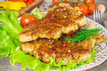 Pork steak with a fork lettuce tomatoes and dill view. Grey food background on wooden table