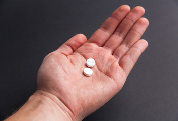 hand holding two white pills on black background medicine pharmacy health