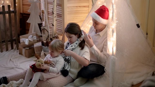 Brother Braided Pigtails to to His Little Sister in New Year and Christmas Decorations