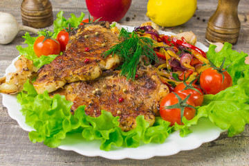 Pork steak with a fork lettuce tomatoes  dill, lemon and Apple in the background, close-up view. Grey food  on wooden table