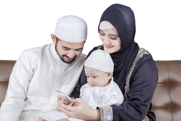 Muslim family sitting on sofa with cellphone
