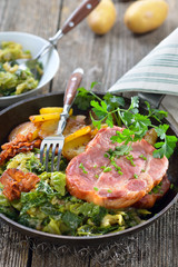 Deftiger geräucherter Kasslernacken mit Speck-Wirsing und Bratkartoffeln in der rustikalen Eisenpfanne serviert - Smoked neck of pork with savoy cabbage, bacon and fried potatoes served in an iron pan