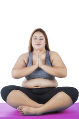 Overweight woman practicing yoga on studio