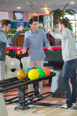 Fototapeta premium Young men bowling, poised to high five