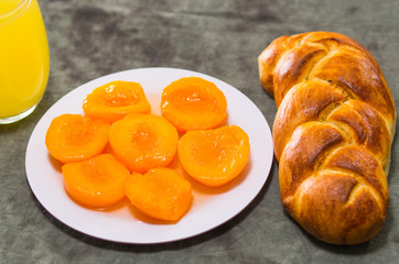 Closeup freshly baked sugar bread with beautiful golden color, white plate of sliced peaches, bakery concept