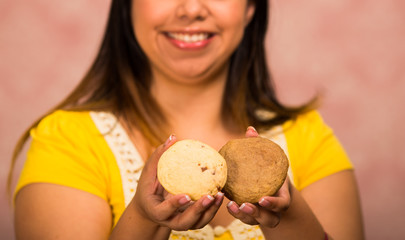 Brunette woman holding delicious brown colored cookies, big smile and ready to take a bite, pastry concept